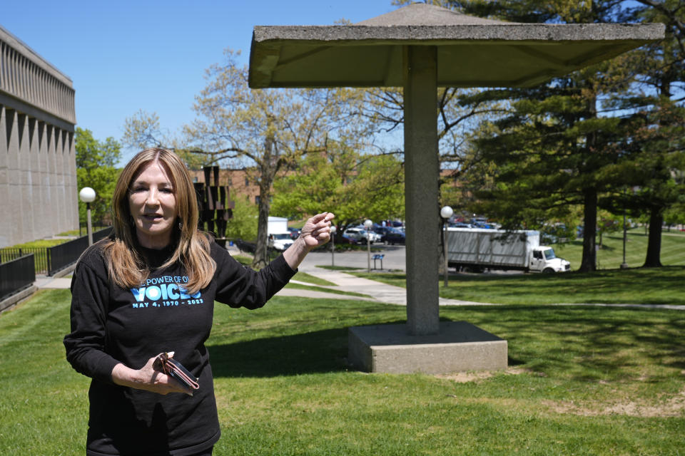 Chic Canfora recounts the events of May 4, 1970, standing at the pagoda where National Guardsmen knelt and shot towards students in the parking lot at rear, during an interview Thursday, May 2, 2024, in Kent, Ohio. (AP Photo/Sue Ogrocki)