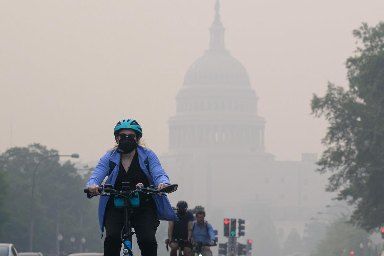 A cyclist rides under a blanket of haze partially obscuring the US Capitol in Washington, DC, on Thursday (AFP via Getty Images)