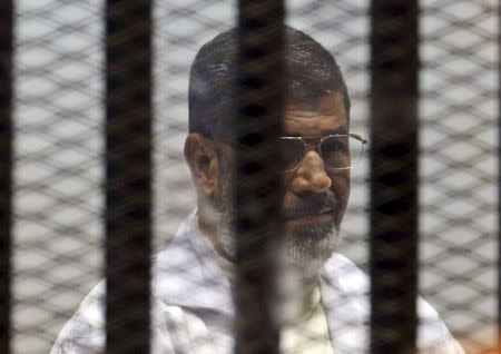 Former Egyptian President Mohamed Mursi sits behind bars at a court on the outskirts of Cairo, Egypt in this December 29, 2014 file photo. REUTERS/Asmaa Waguih/Files