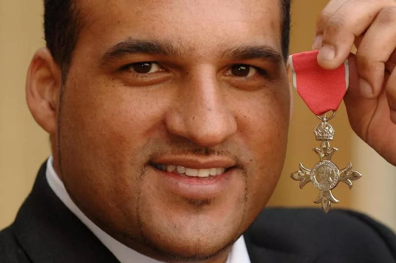 Michael Caines holding up MBE