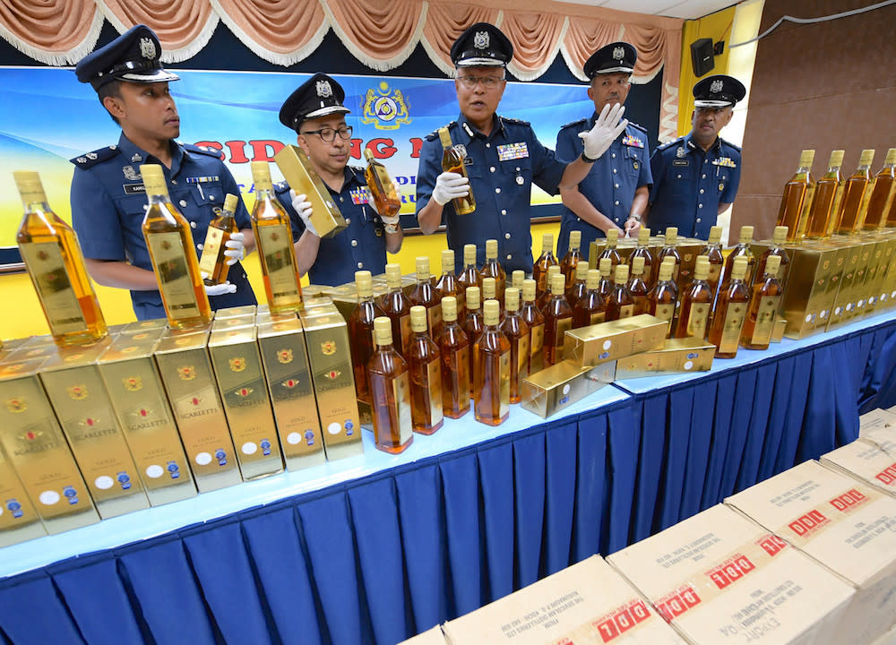 Customs deputy director (Enforcement and Compliance) Datuk Seri Zulkifli Yahya poses for pictures with the seized alcohol during a press conference in Alor Setar October 4, 2018. — Bernama pic