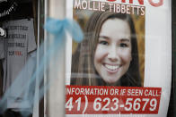 FILE - In this Aug. 21, 2018, file photo, a poster for then missing University of Iowa student Mollie Tibbetts hangs in the window of a local business in Brooklyn, Iowa. Tibbetts was reported missing from her hometown in July after going for a run and her body was found Aug. 21. Recent killings of women who were attacked while engaged in the sports they love have raised questions about how women can defend themselves and why they must be ready to fight off attackers in the first place. (AP Photo/Charlie Neibergall, File)