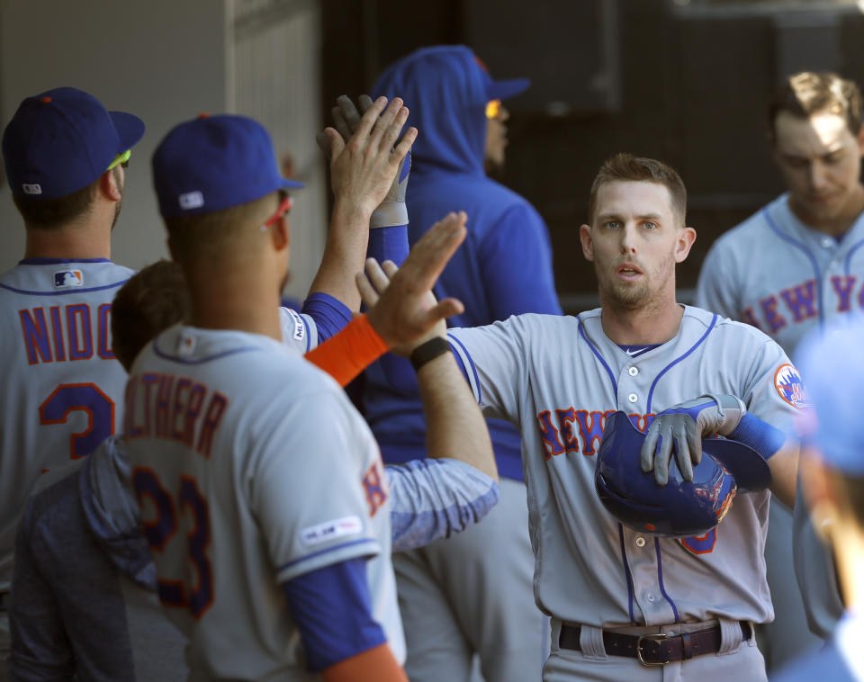 New York Mets' Jeff McNeil, right, celebrates in the dugout after scoring on Robinson Cano's RBI double off Chicago White Sox starting pitcher Dylan Cease, during the sixth inning of a baseball game Thursday, Aug. 1, 2019, in Chicago. (AP Photo/Charles Rex Arbogast)