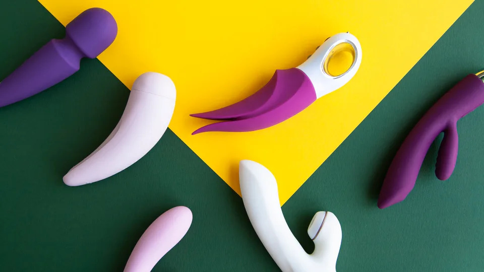 Vibrators in different shapes and colors on yellow and green background