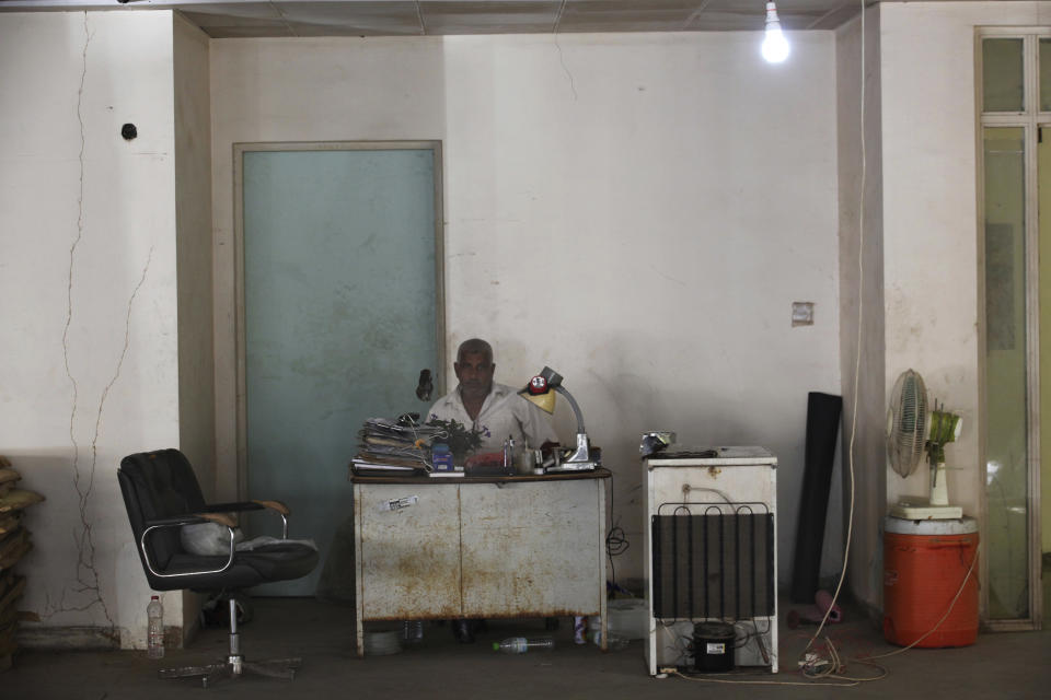 In this Thursday, Dec. 13, 2018 photograph, a man sits behind a desk in the closed Aden Governorate General Hospital in Aden, Yemen. Land mines scattered by Yemen’s Houthi rebels will remain a threat even if the latest negotiations succeed in halting the civil war in the Arab world’s poorest country. Yemen is also littered with unexploded cluster munitions and bombs dropped by the Saudi-led coalition, including some made in the United States. (AP Photo/Jon Gambrell)