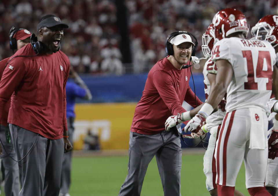 Oklahoma head coach Lincoln Riley, center, congratulates wide receiver Charleston Rambo (14) after Rambo scored a touchdowns, during the second half of the Orange Bowl NCAA college football game against Alabama, Saturday, Dec. 29, 2018, in Miami Gardens, Fla. (AP Photo/Lynne Sladky)