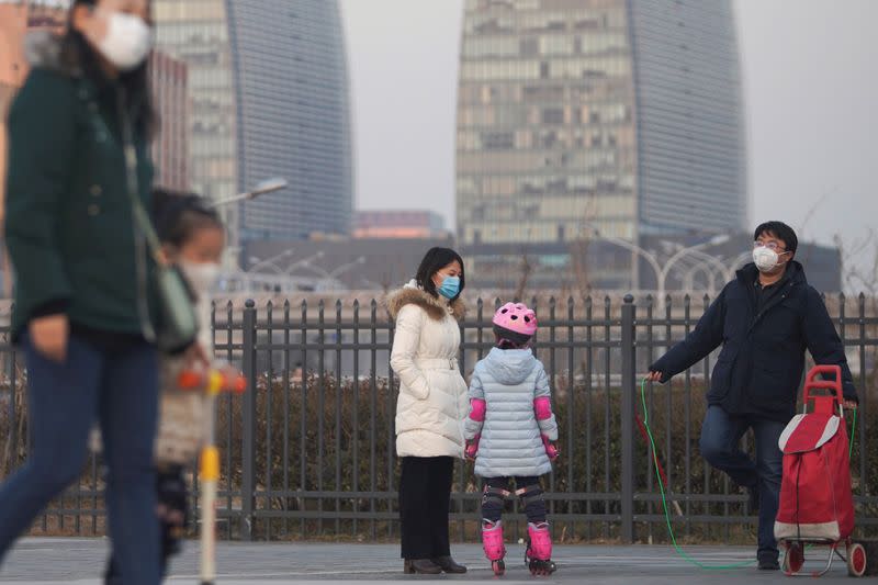 People wear face masks at a square in Beijing