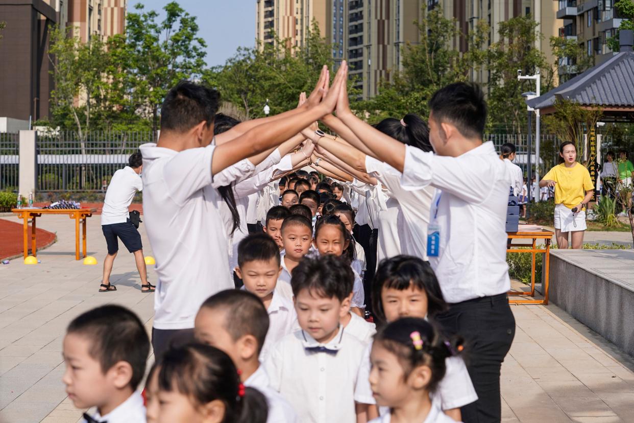 Elementary school students are welcomed by teachers as they arrive at school on the first day of the new semester in Wuhan in China's central Hubei province on Sept. 1, 2020.