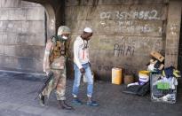 A member of the South African National Defense Force escorts a homeless men in Johannesburg