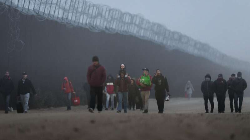 Migrants walk along the U.S.-Mexico border