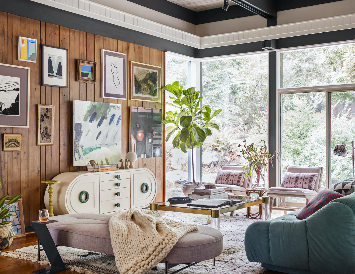  An eclectic living room with a gallery wall on a wood-clad wall. 