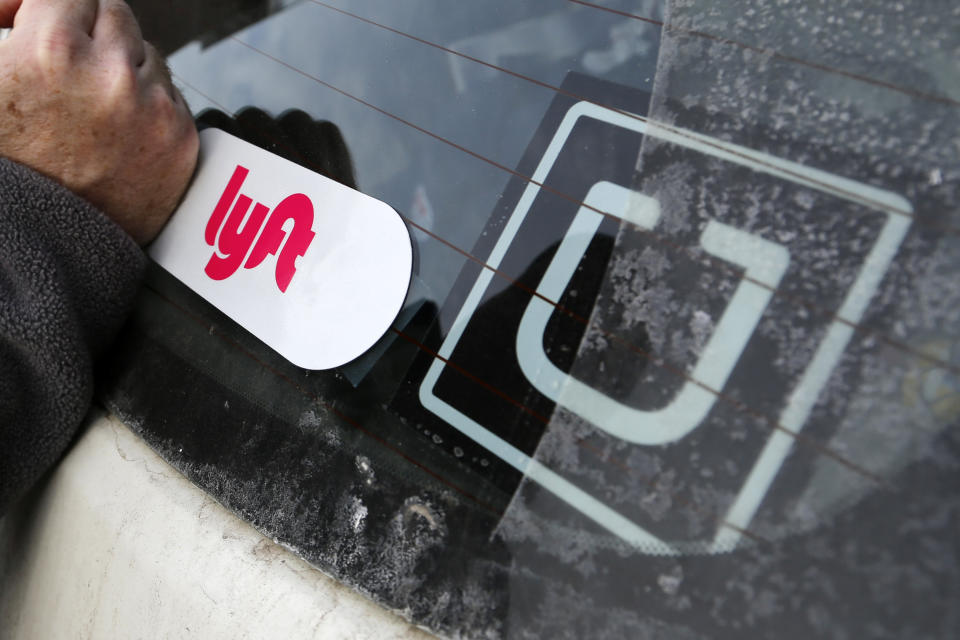 FILE- In this Jan. 31, 2018, file photo, a Lyft logo is installed on a Lyft driver's car next to an Uber sticker in Pittsburgh. The “gig” economy might not be the new frontier for America’s workforce after all. From Uber to Lyft to TaskRabbit to YourMechanic, so-called gig work has been widely seen as ideally suited for people who want the flexibility and independence that traditional jobs don’t offer. Yet the evidence is growing that over time, they don’t deliver the financial returns many expect. (AP Photo/Gene J. Puskar, File)