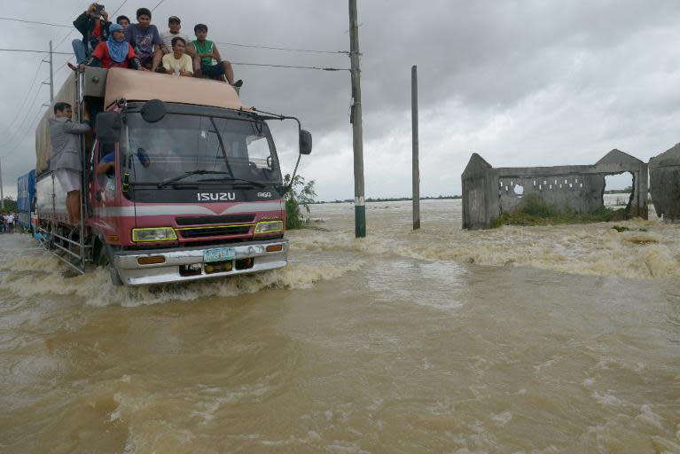 Vehicles drive though flood waters on a road in the northern Philippines on October 12, 2013