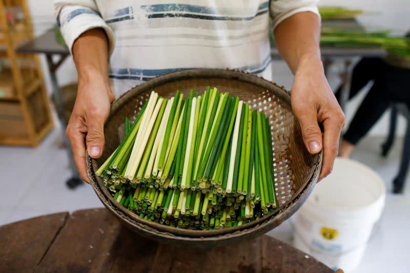 Tran Minh Tien, the owner of 3T shop, holds a basket of processed grass straws at his workshop in Long An province