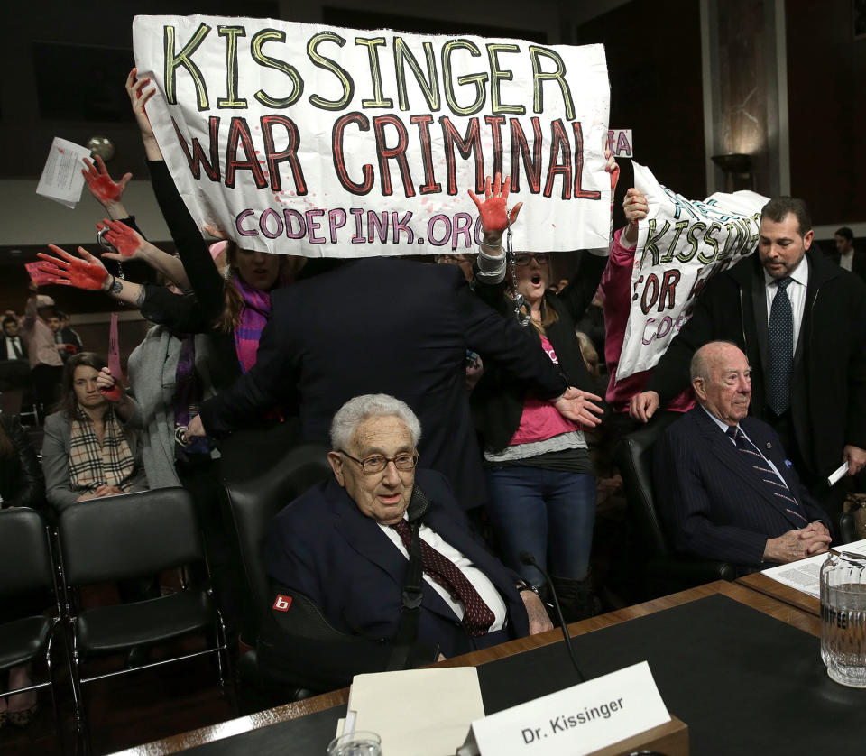 WASHINGTON, DC - JANUARY 29: Protesters shout "Arrest Henry Kissinger for war crimes" as (L-R) Former U.S. Secretary of State Henry Kissinger; former U.S. Secretary of State George Shultz and and former U.S. Secretary of State Madeleine Albright wait to testify before the Senate Armed Services Committee January 29, 2015 in Washington, DC. The committee heard testimony from Kissinger, Schultz and Albright on the topic of global challenges and U.S. national security strategy. (Photo by Win McNamee/Getty Images)