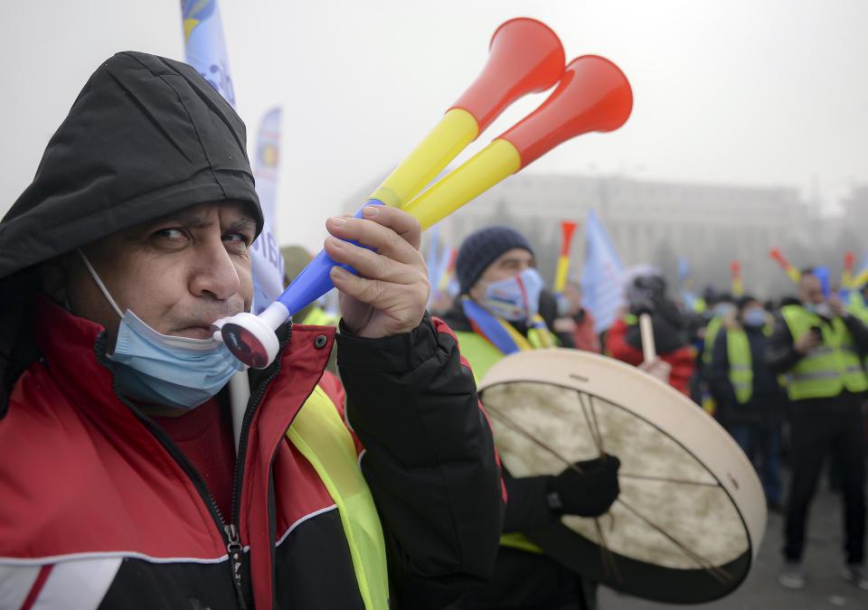 A man blows a horn at a rally of policemen and retired members of the military in Bucharest, Romania, Tuesday, Feb. 23, 2021. Hundreds of Romanian policemen have marched in protest of planned austerity measures that envisage freezing of salaries in the public sector.(AP Photo/Alexandru Dobre)