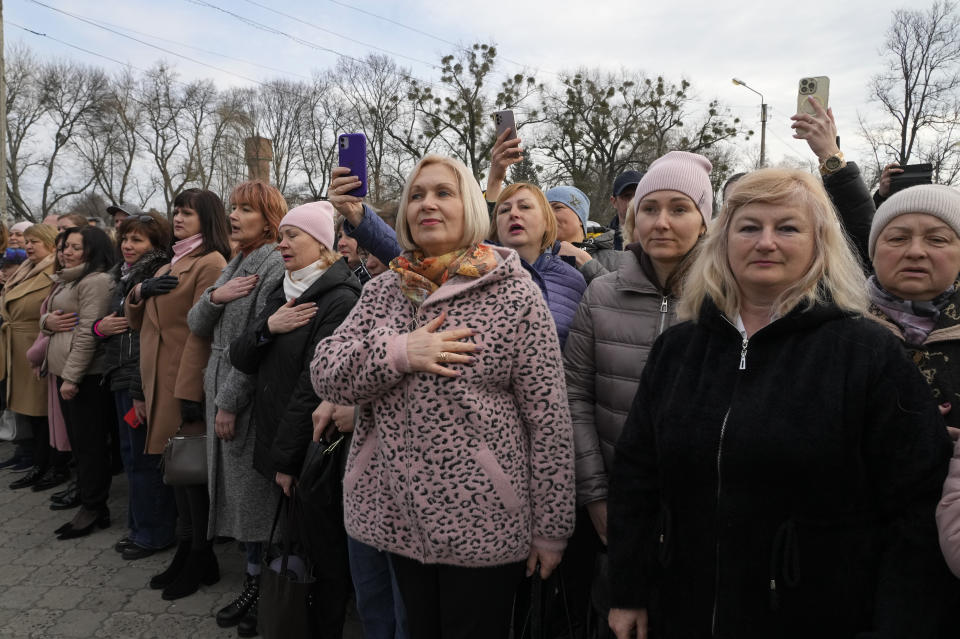 People sing the national anthem during a visit by Ukrainian President Volodymyr Zelenskyy in Okhtyrka in the Sumy region of Ukraine, Tuesday March 28, 2023. (AP Photo/Efrem Lukatsky)