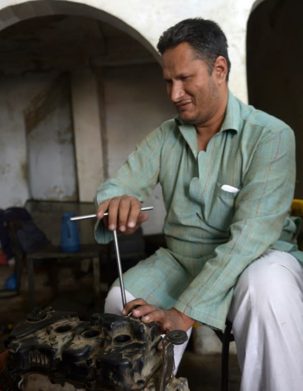 Blind mechanic Asif Patel works on a car engine at his workshop in Karachi