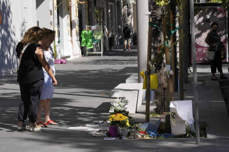 People stop where the street vendor Alika Ogochukwu was killed, in Civitanova Marche, Italy, Saturday, Aug. 6, 2022. The brutal killing of a Nigerian immigrant in broad daylight has sparked a debate in this well-to-do Adriatic beach community over whether the attack by an Italian man with a court-documented history of mental illness was racially motivated. It will go to the streets on Saturday, Aug. 6 when a Black Italian activists from all over Italy march through the town demanding justice for Alika Ogorchukwu. (AP Photo/Antonio Calanni)