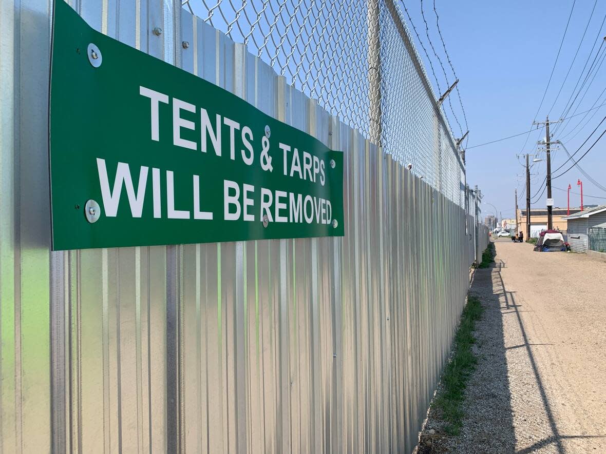 A sign in an alley off 106th Avenue in Chinatown warns that tents and tarps will be removed. The signs were put up by the Chinatown and Area BIA, which acknowledges it does not have the authority to enforce removal.  (Paige Parsons/CBC - image credit)