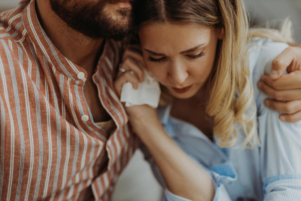 Two people embracing, one comforting the other who appears upset