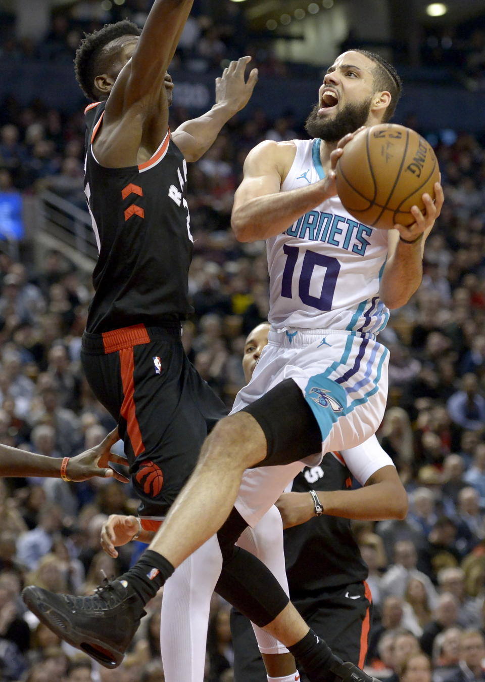 Charlotte Hornets forward Caleb Martin (10) drives to the net as Toronto Raptors forward Chris Boucher (25) defends during second-half NBA basketball game action in Toronto, Friday, Feb. 28, 2020. (Nathan Denette/The Canadian Press via AP)