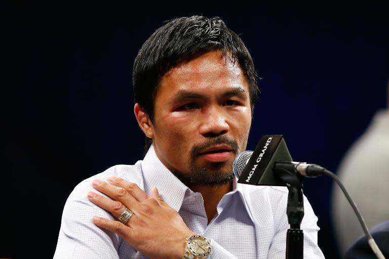 Manny Pacquiao points to his injured right shoulder during the post-fight news conference after losing to Floyd Mayweather in their welterweight unification championship bout on May 2, 2015