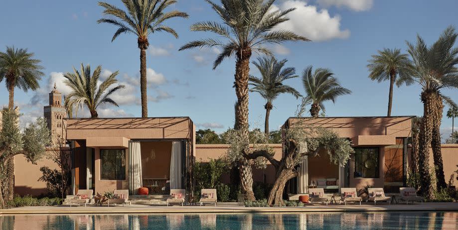 a pool with palm trees and royal mansour in the background