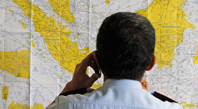 An airport official checks a map of Indonesia at the crisis centre set up by local authority for the missing AirAsia flight QZ8501 at Juanda International Airport in Surabaya, East Java, Indonesia. Photo: AP