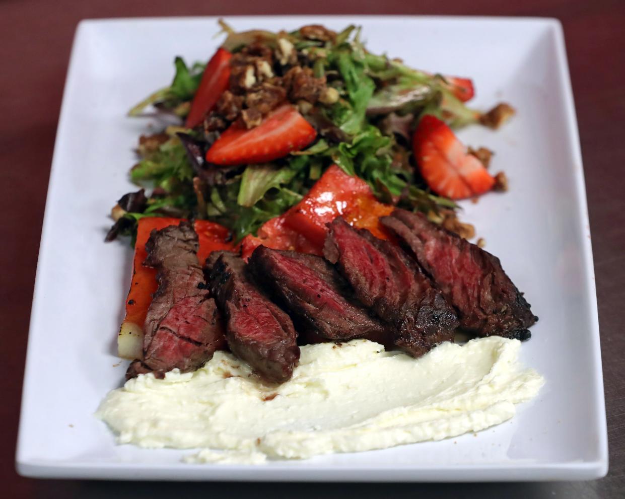 The Eye Opener's watermelon steak salad, a mix of greens, candied pecans, strawberries and bruleed watermelon, is served with grilled hanger steak and feta mousse Wednesday, April 24, 2024, in Akron, Ohio.