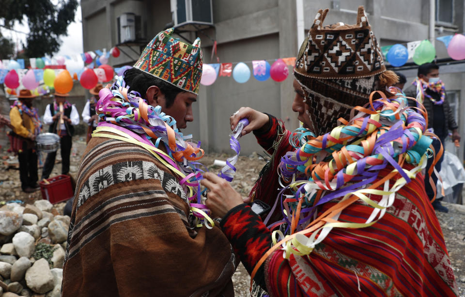 Guías espirituales se envuelven mútuamente en serpentinas durante la celebración del "Martes de Challa", en la cual la gente compra comida, lanza dulces, quema incienso y decora sus casas, negocios y autos para agradecer a la Pachamama o Madre Tierra, en La Paz, Bolivia, el martes 16 de febrero de 2021. (AP Foto/Juan Karita)