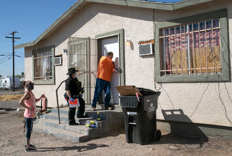 A maintenance man breaks the lock of a house as Maricopa County constable Darlene Martinez serves an eviction order on Oct. 1, 2020, in Phoenix.