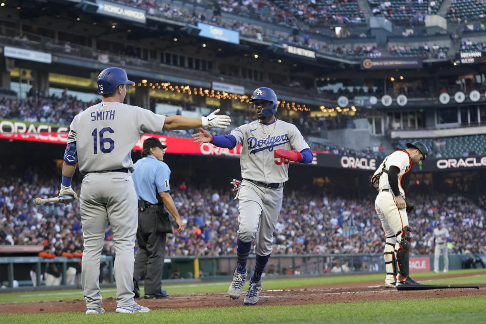 Los Angeles Dodgers' Mookie Betts, middle, is congratulated by Will Smith (16) after scoring against the San Francisco Giants during the third inning of a baseball game in San Francisco, Monday, Aug. 1, 2022. (AP Photo/Jeff Chiu)