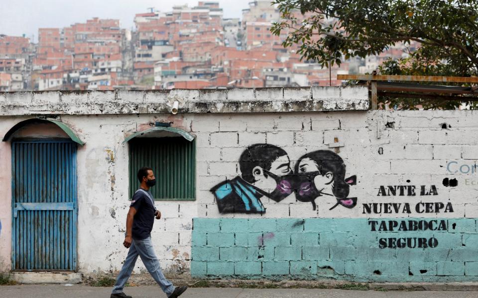 Graffiti reads "In the face of the new strain, face mask for sure" amid a spike in infections in Caracas - Reuters