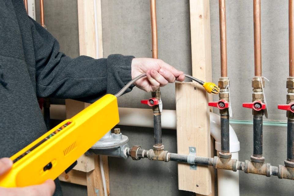 A plumber checking for gas leaks inside an old home during renovation.