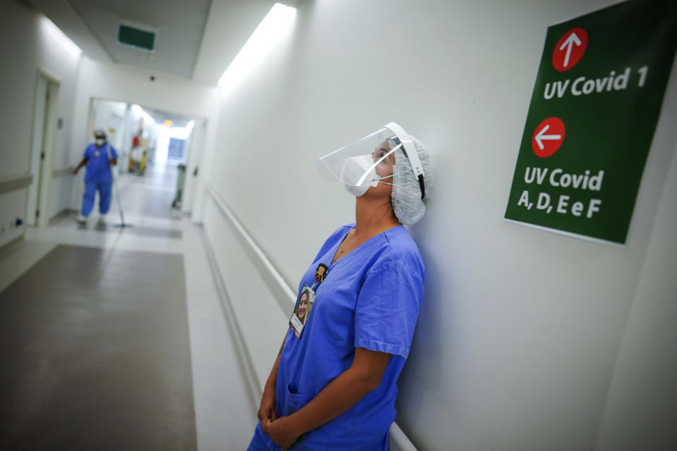 FILE - In this March 19, 2021 file photo, a healthcare worker lends against a wall in the corridor of an ICU unit for COVID-19 patients at the Hospital das Clinicas, in Porto Alegre, Brazil. The withdrawal of generous pandemic welfare payments comes at a time when there is no near-term hope of mass vaccination to safeguard the labor force. (AP Photo/Jefferson Bernardes, File)