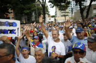 CORRECTS WHY SUPPORTERS ARE RAISING THEIR HANDS - Supporters of opposition leader and self-proclaimed interim president of Venezuela Juan Guaido show their approval after learning that the National Assembly approved Venezuela's return to the Inter-American Treaty of Reciprocal Assistance, at a rally in Caracas, Venezuela, Tuesday, July 23, 2019. (AP Photo/Ariana Cubillos)