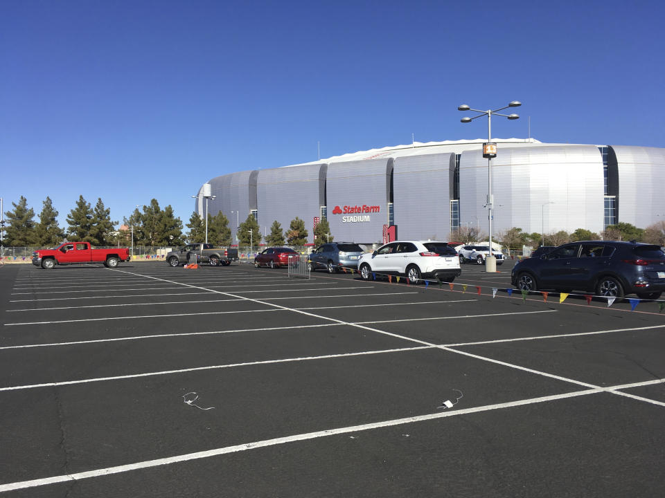 Drivers wait in line to get the COVID-19 vaccine in the parking lot of the State Farm Stadium