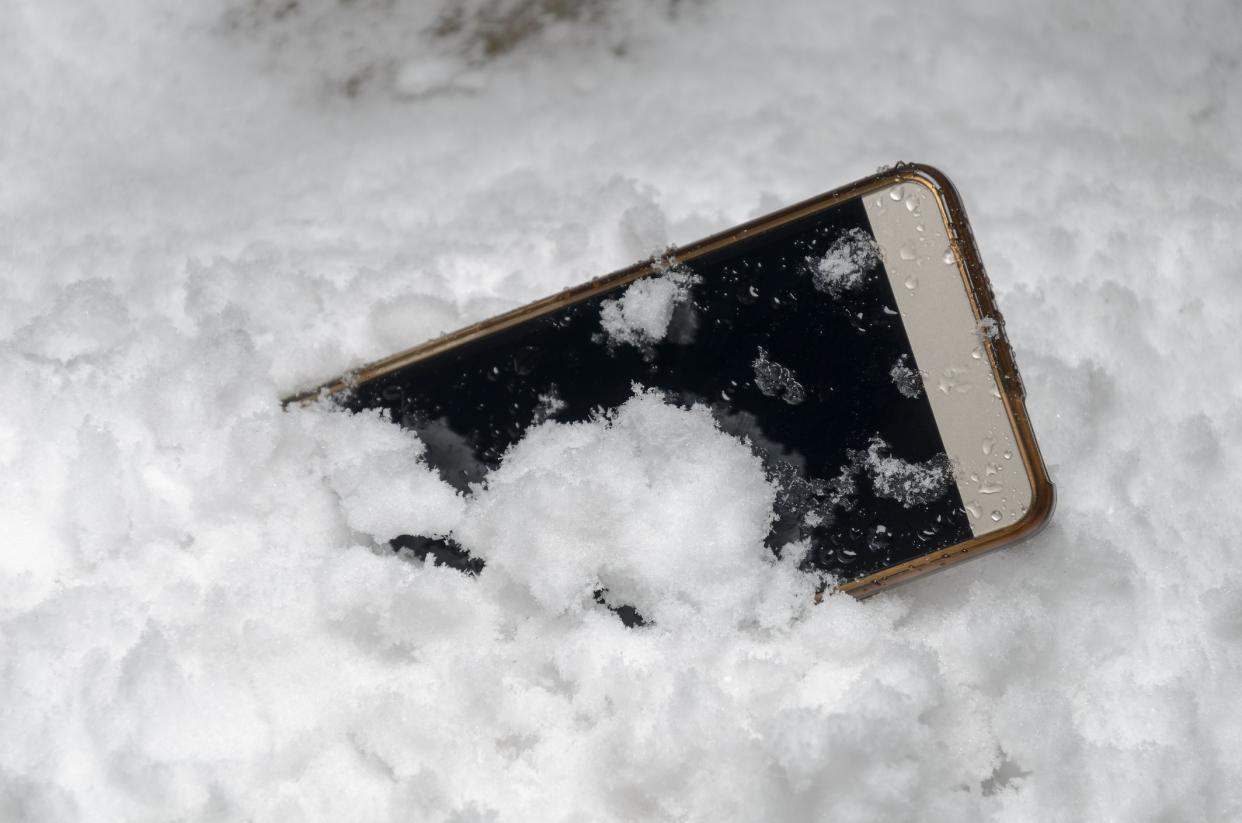 Mobile phone fell and lies in a snow drift under the open sky