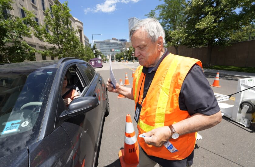 Election judge Adam Ballinger accepts a ballot from a motorist passing through a drive-up polling location outside the Denver Elections Division headquarters Tuesday, June 28, 2022, in Denver. (AP Photo/David Zalubowski)