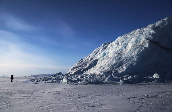 NASA project scientist Nathan Kurtz surveys an iceberg locked in sea ice near Pituffik, Greenland.