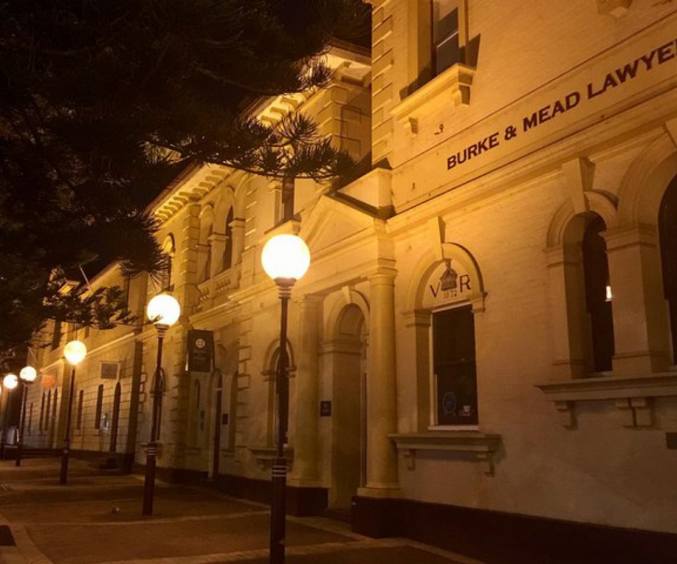 Image of a white heritage building in Newcastle at night lit by street lamps.
