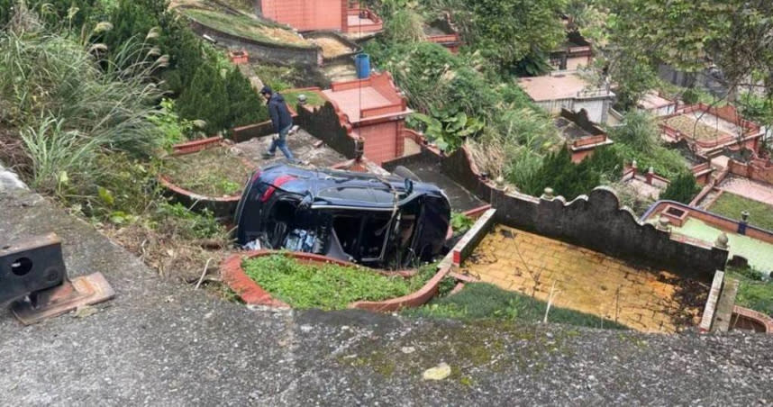 汐止第一公墓一早傳出小客車翻落邊坡意外，只見車輛當場卡在他人墳墓之中且車體嚴重毀損。（圖／翻攝畫面）