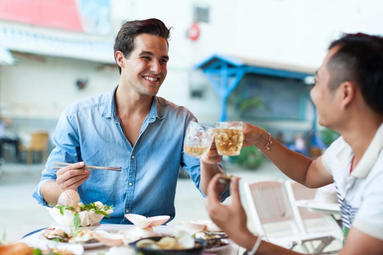 Cheerful young men eating at a restaurant in Asian country