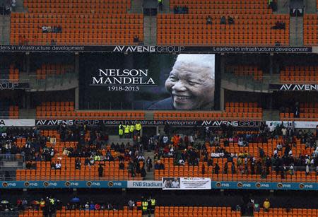 A picture of former South African President Nelson Mandela is shown on a giant screen at the First National Bank (FNB) Stadium, also known as Soccer City, ahead of Mandela's national memorial service in Johannesburg December 10, 2013. World leaders from U.S. President Barack Obama to Cuba's Raul Castro joined thousands of South Africans to honour Mandela on Tuesday in a memorial that will celebrate his gift for uniting enemies across political and racial divides. REUTERS/Yves Herman