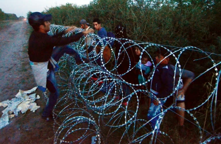 Migrants from several countries jump over a razor-wire fence at the Hungarian-Serbian border at Roszke village in Hungary, August 30, 2015