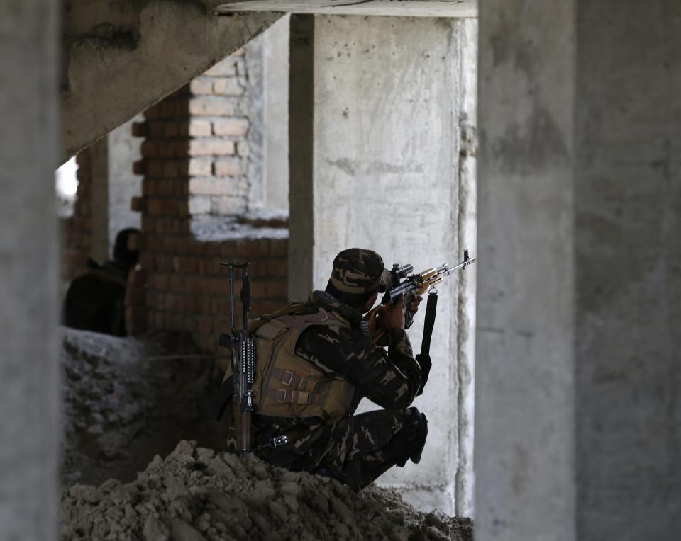 Afghan security personnel take position at the site of an attack, opposite a building where unidentified militants are located at, north of Kabul International Airport in Kabul