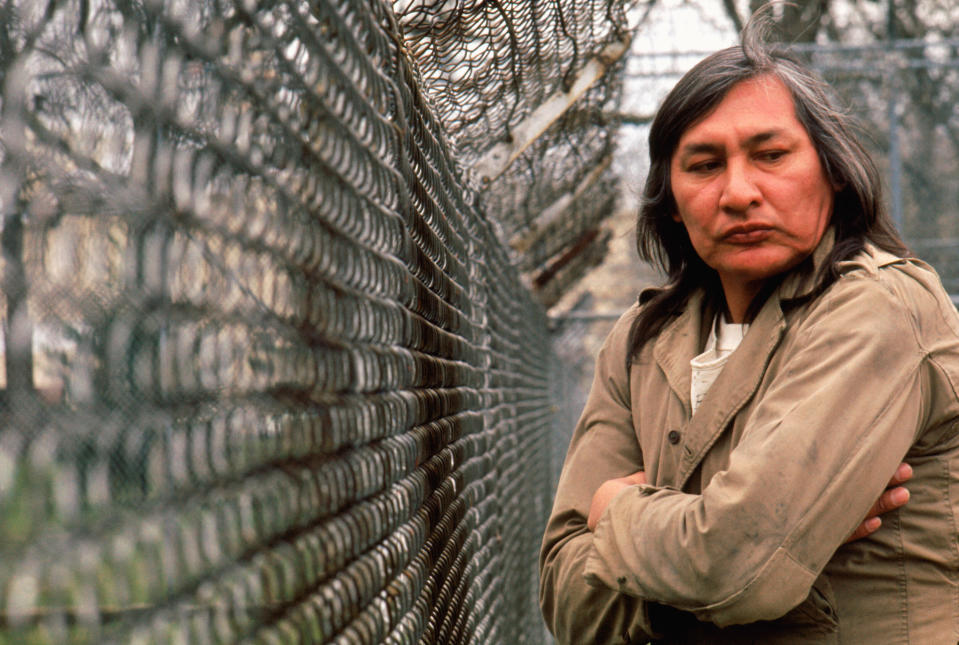 Chief Bromden standing at the asylum's fence