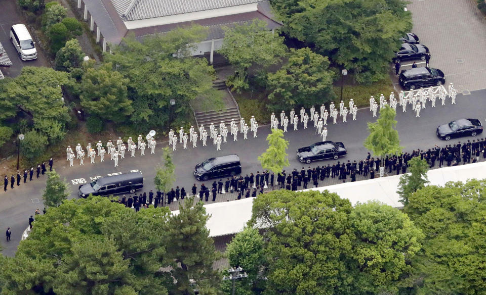 The hearse, left, carrying the body of former Japanese Prime Minister Shinzo Abe leaves Zojoji temple after his funeral in Tokyo on Tuesday, July 12, 2022. Abe was assassinated Friday while campaigning in Nara, western Japan.(Kyodo News via AP)