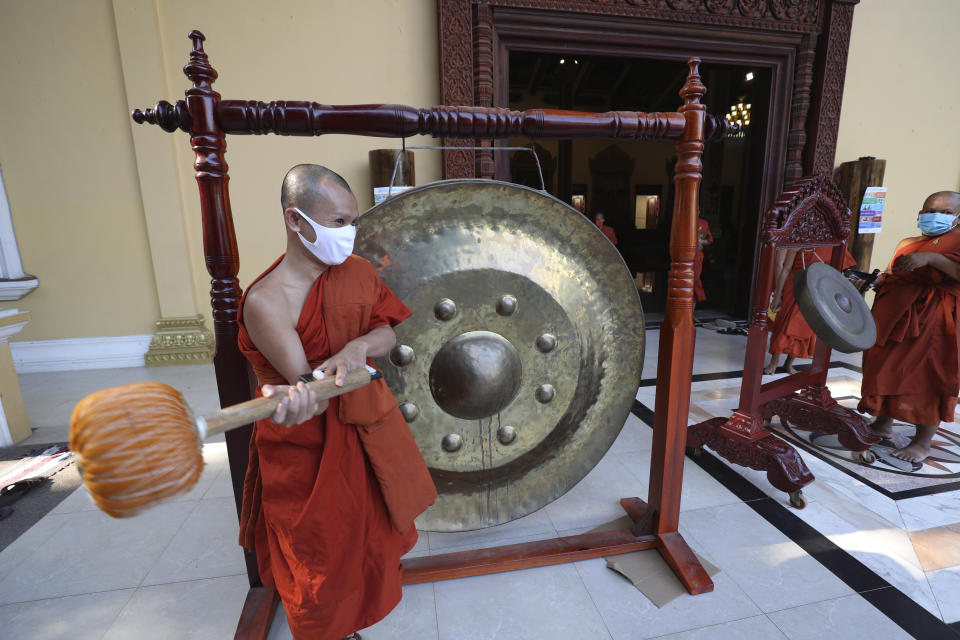 A Buddhist monk strikes a gong at a pagoda in Phnom Penh, Cambodia, Monday, Mar. 23, 2020. Buddhist pagodas in Cambodia on Monday offered prayer, chanting along with strikes of gongs and drums in hopes of chasing away the new coronavirus. (AP Photo/Heng Sinith)